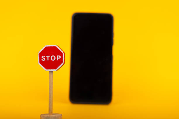 istock Stop Signal with Blurred Smartphone on Yellow 2164323957