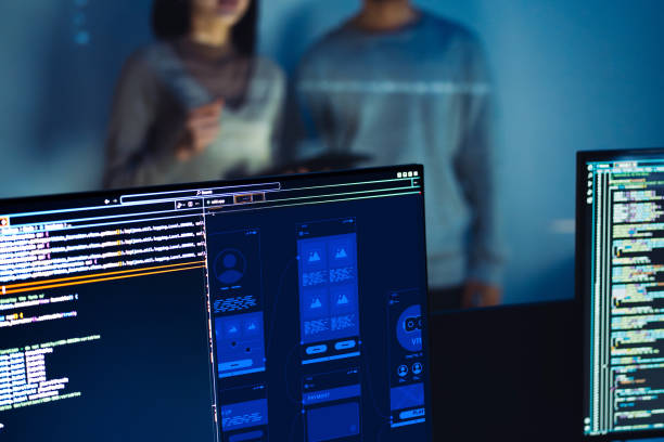 istock UX designer works on a tablet while a colleague tests  application in the background in office 2164324302