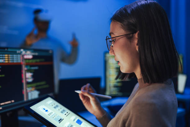 istock Asian UX designer works on a tablet while a colleague tests a VR application ,integration of user experience design and virtual reality development in a modern tech workspace 2164324583