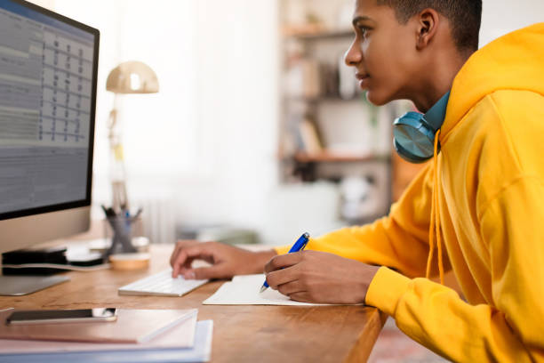 istock Focused teen guy studying at computer desk 2164328061