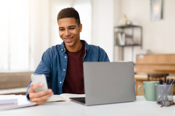 istock Man smiling at phone with laptop on desk 2164328177