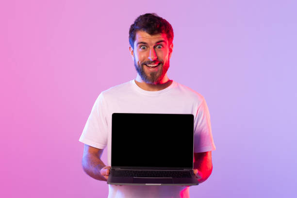 istock Young Man Holding Laptop With Black Screen in Studio Lighting 2164328210