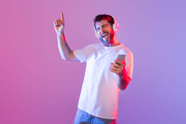 istock Man Enjoying Music With Headphones While Dancing Indoors at Night 2164328219