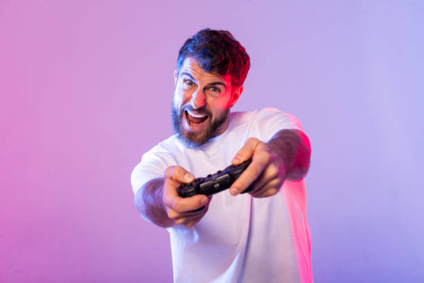 istock Enthusiastic Man Playing Video Games With Controller in Colorful Studio 2164328225