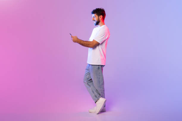 istock Man in White T-Shirt Holding Cell Phone 2164328246