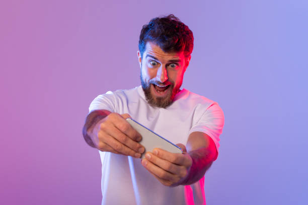 istock Excited Bearded Man Playing Game on Smartphone 2164328277