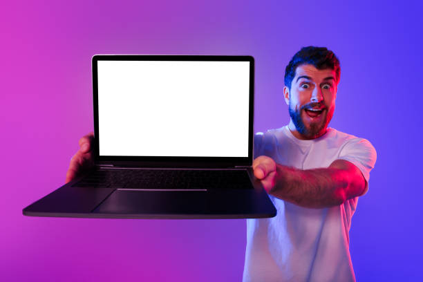 istock Emotional guy showcasing blank laptop screen advertising websites, neon backdrop 2164328352