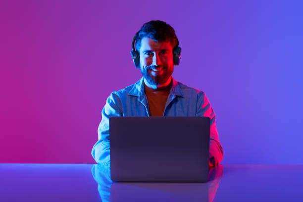 istock freelancer man with headset working on laptop in neon studio 2164328361