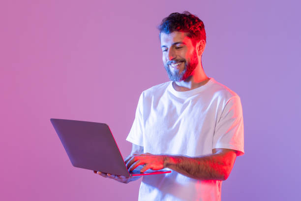 istock Man in White Shirt Using Laptop Computer in Neon Light 2164329003