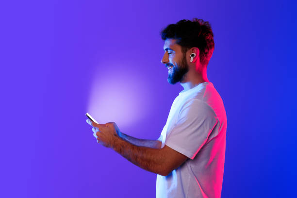 istock Young caucasian man holds phone enjoying music through earbuds, studio 2164329015