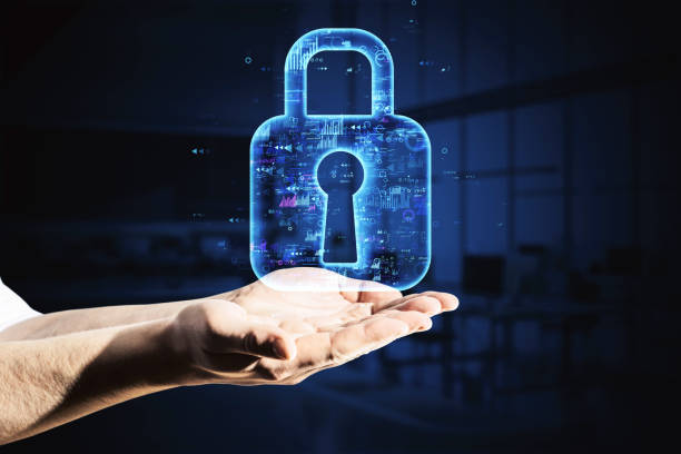 istock Hands holding a digital lock hologram on a dark background in an office setting. 2164330596