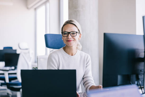istock Businesswoman giving a cheerful look at the camera while working 2164330765