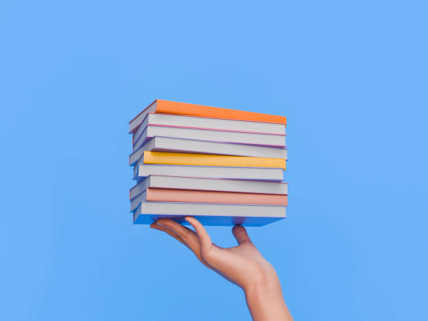 istock Hand Holding Stack of Colorful Books Against Blue Background 2164331616