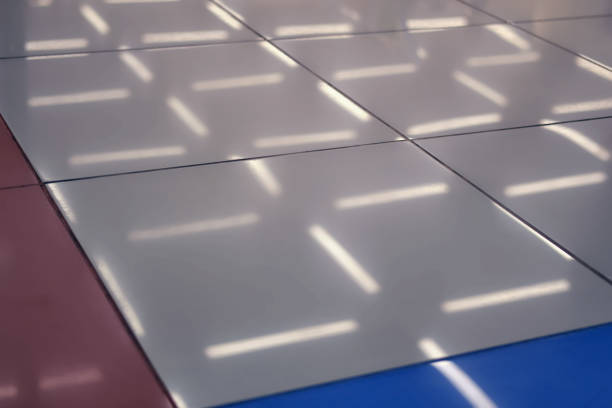Reflective white and colored floor tiles with fluorescent light reflections. Abstract interior design.