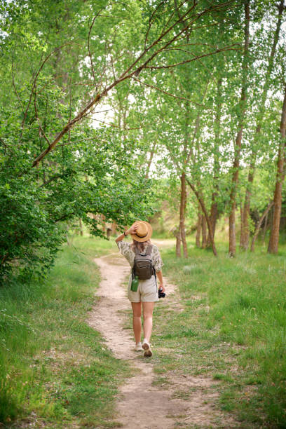istock Young woman enjoying nature while taking photographs on a lush forest path during daylight 2164331811