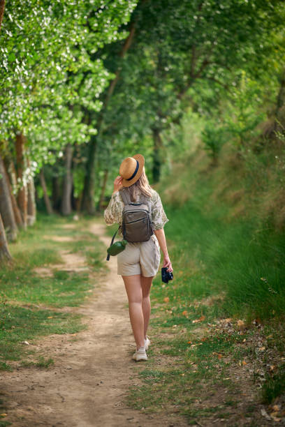 istock Young woman enjoying nature while taking photographs on a lush forest path during daylight 2164331878