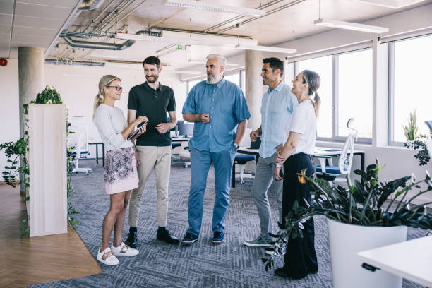 istock A team of employees is standing together in a casual office setting, discussing a project 2164331973