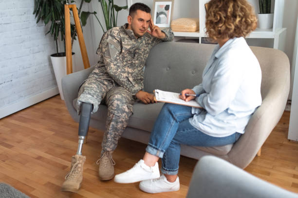 istock Veteran in camouflage uniform with a prosthetic leg in a counseling session 2164332513