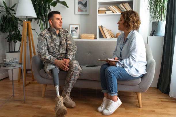 istock Veteran in military uniform with a prosthetic leg talking with therapist 2164332568