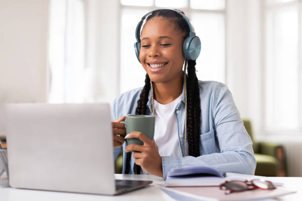 istock Smiling black female student with headphones studying at laptop 2164333710