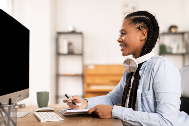 istock Smiling lady student with headphones taking notes during an online class 2164333736