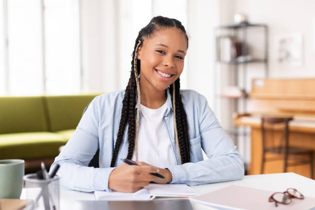 istock Smiling african american lady student studying at home 2164333783