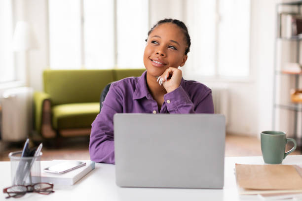 Daydreaming lady student with laptop in cozy home setup