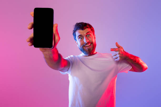 istock Man in White Shirt Holding Cell Phone With Blank Screen 2164333965