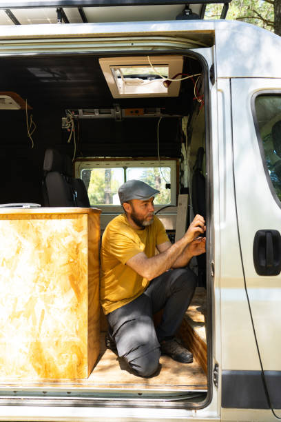 istock Caucasian man working customizing a camper van putting a thermal insulator on it 2164337545