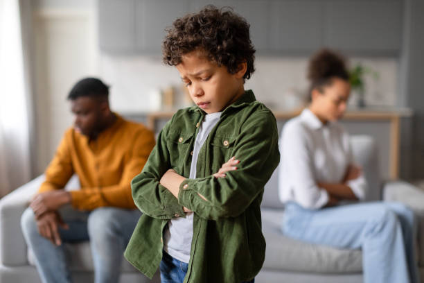 istock Upset child with arms crossed, parents in background 2164339080