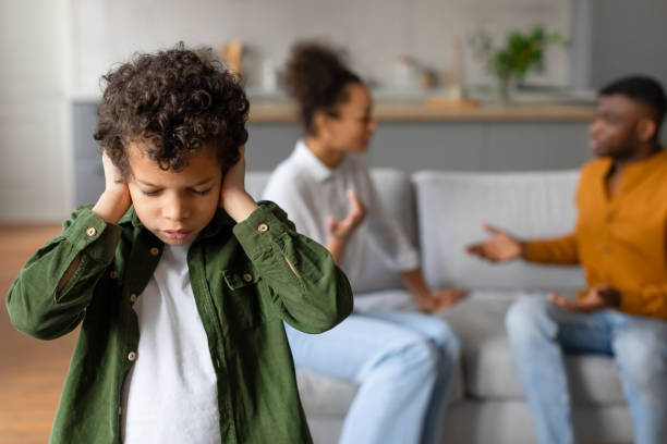 istock Child boy covers ears while parents argue in the background 2164339096
