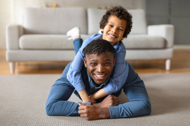 Cheerful black boy on father's back, sharing fun moment
