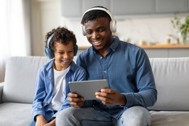 istock Joyful black father and son using tablet with headphones 2164339123