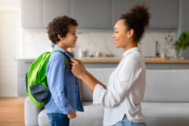 istock Happy black mother preparing child boy with backpack for school 2164339136