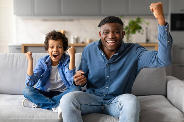 istock Joyful black father and son celebrating victory at home 2164339152