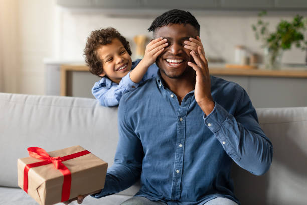istock Black son surprises dad with gift, covering his eyes from back 2164339187