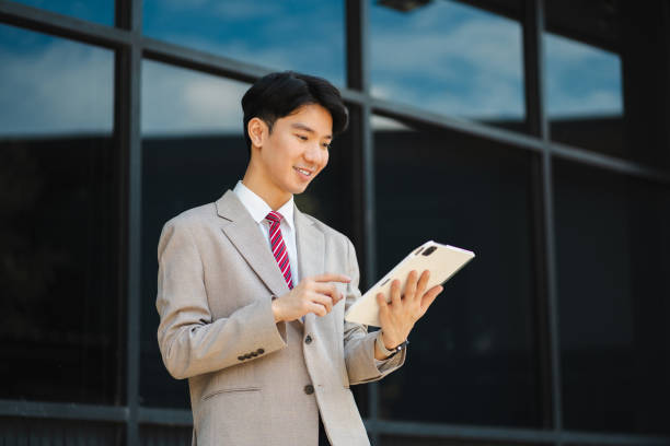 istock Professional businessman using digital tablet computer, smartphone and holding coffee to go while working at office. 2164339541
