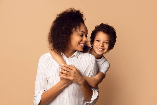 istock Joyful Mother Embracing Her Young Son Against Warm Beige Background 2164343085