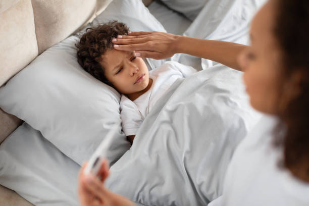 istock Young Mother Checking Her Childs Temperature in Bed During Morning 2164343104
