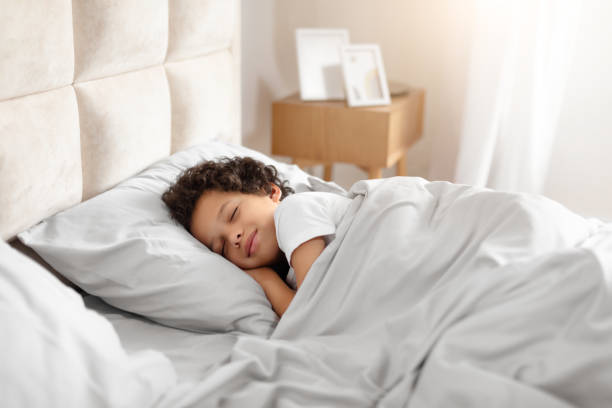 istock Little Boy Sleeping in Bed With White Comforter 2164343121