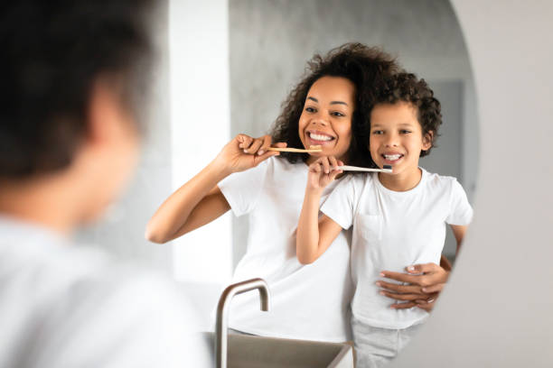 istock Woman Brushing Teeth Next to Child in Bathroom 2164343124