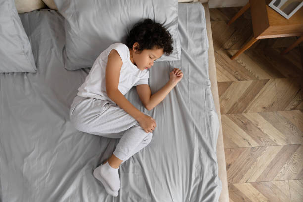istock Young Child Sleeping Peacefully on Grey Bed, Top View 2164343131