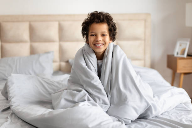 istock African American Child Wrapped in Blanket on Bed 2164343136
