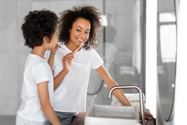istock Black Woman Brushing Her Teeth Next to a Young Boy 2164343156