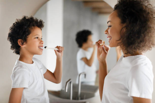 istock Woman Brushing Her Teeth Next to Little Boy 2164343157