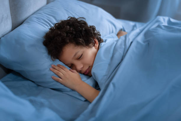 istock Young Boy Sleeping in Bed With Blue Sheets at Night 2164343181