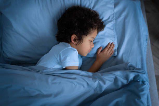 istock Small Child Laying in Bed With Blue Comforter, Top View 2164343182