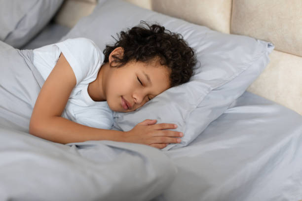 istock Young Child Sleeping Comfortably in Bed With Pillow 2164343184