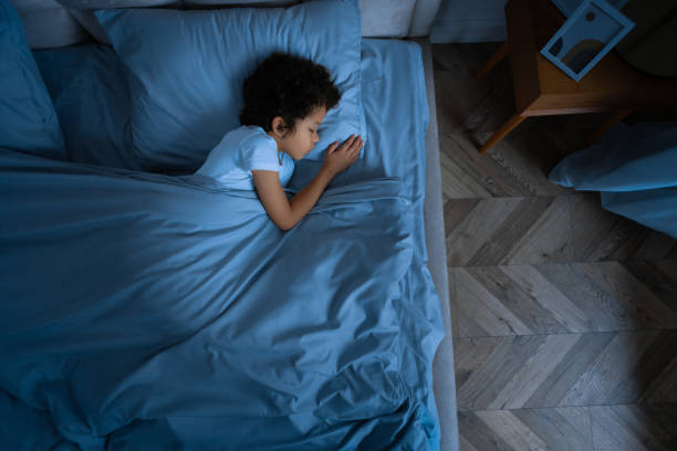 Little Boy Laying in Bed With Blue Comforter, View Above