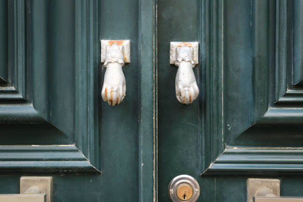 istock Old doorknocker with hand shape on old wooden door 2164349187